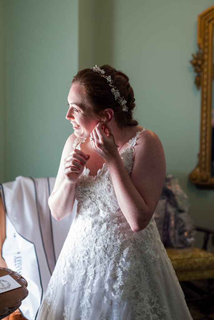 Bride putting in her earrings while looking out the window