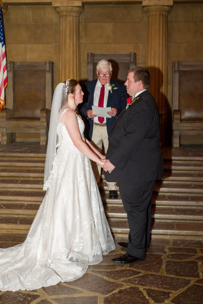 Bride and groom holding hands during the ceremony in masonic temple