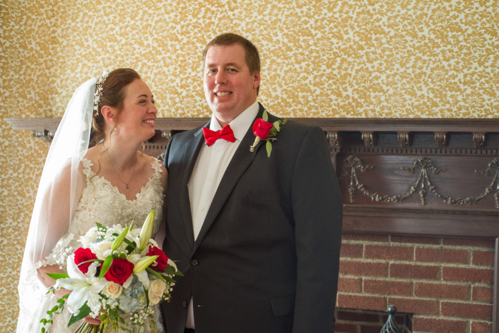 Groom smiling at the camera and bride smiling at groom at masonic temple