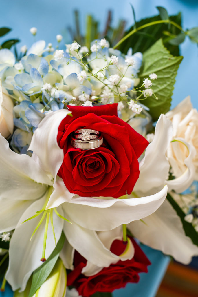wedding rings on bouquet of lilies and roses