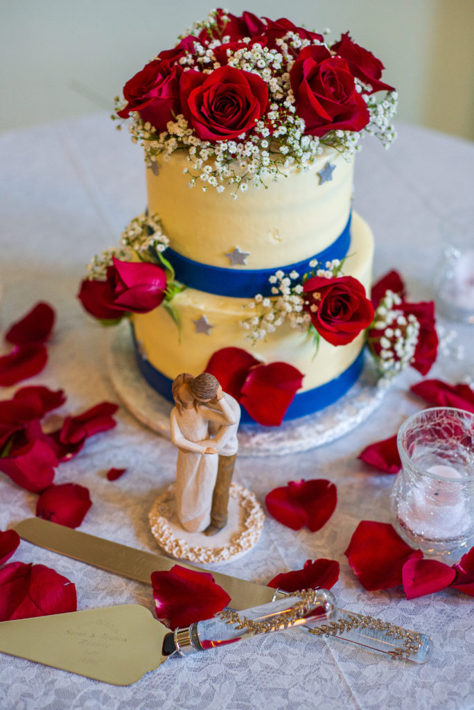 beautiful wedding cake with blue ribbon and red roses