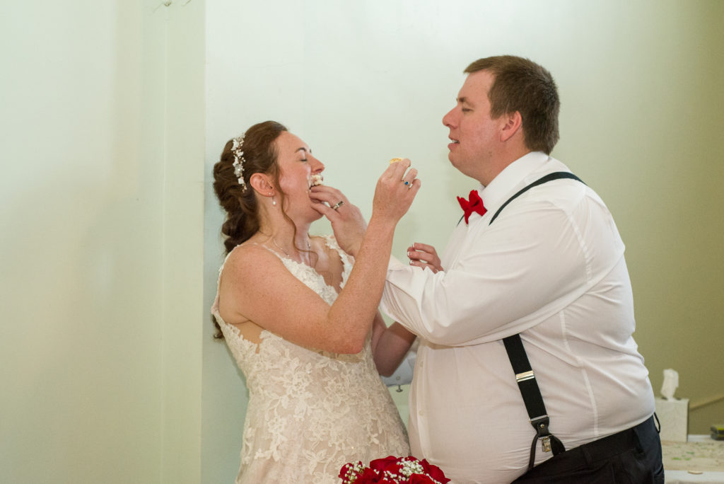 bride and groom feeding each other cake, groom shoving it into bride's face
