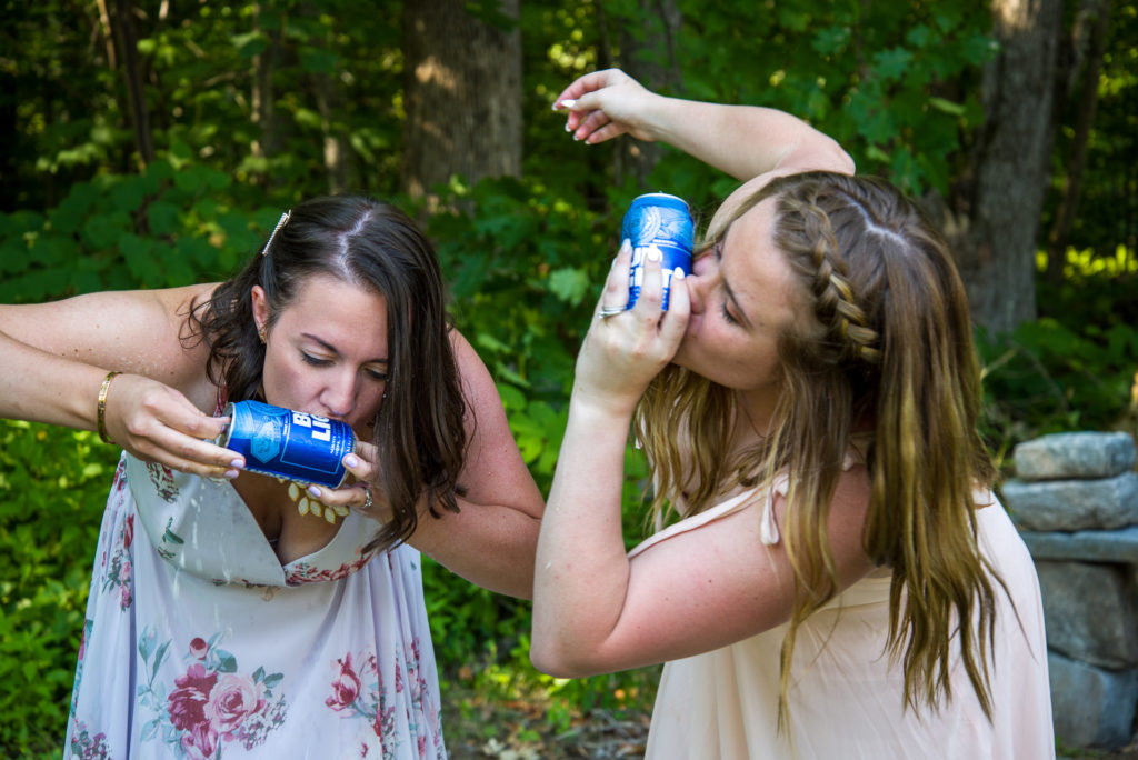 bride and maid of honor shotgunning a beer