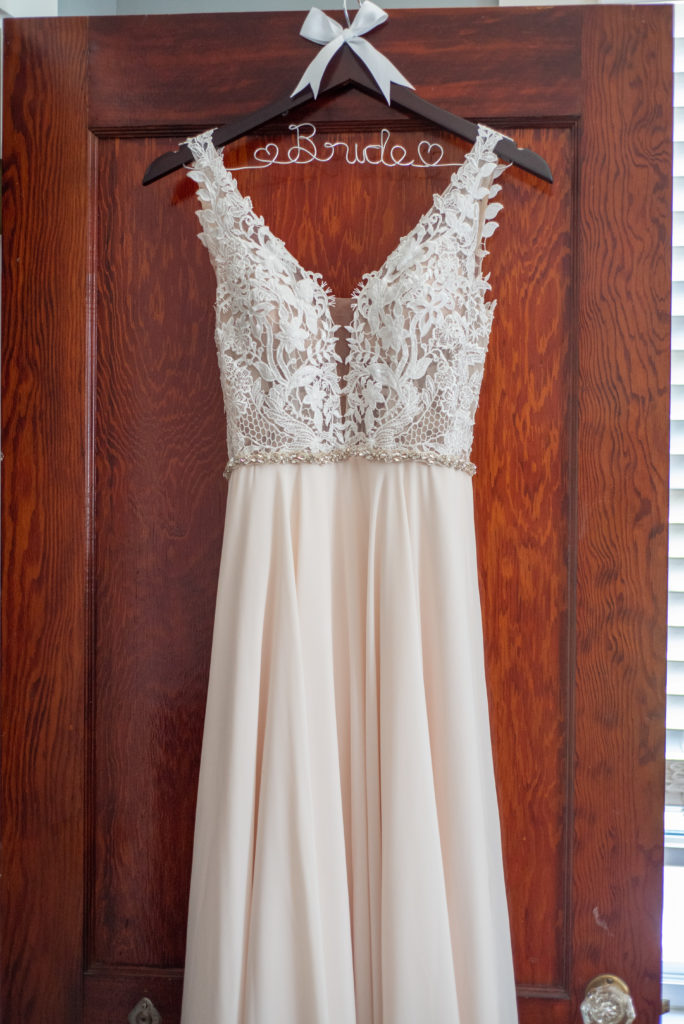 wedding dress hanging on a bride hanger on the door