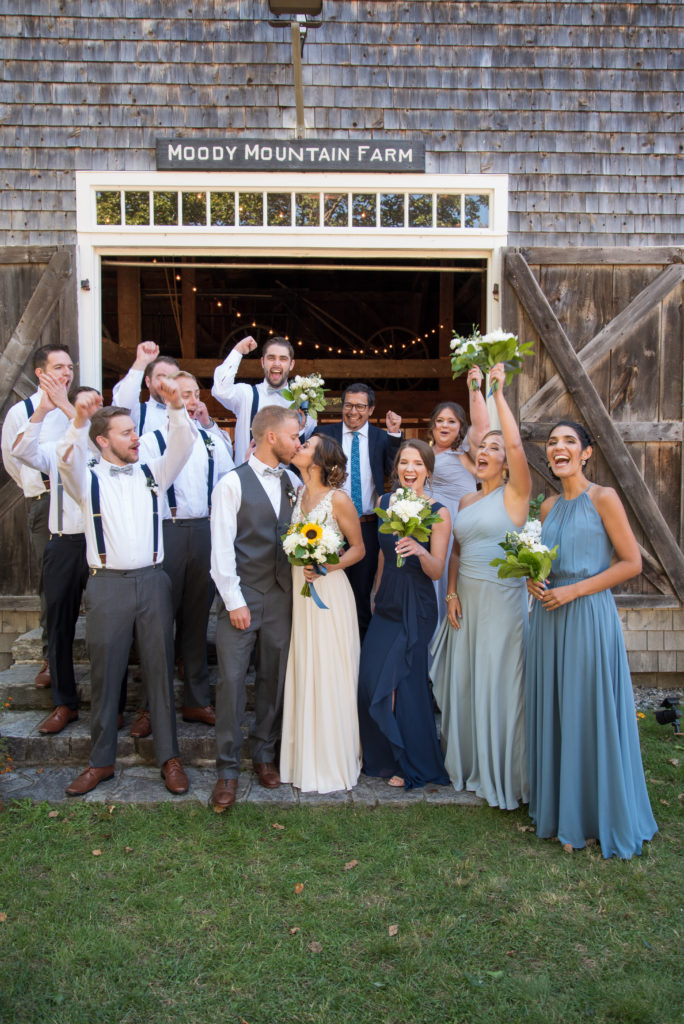 bride and groom kissing while bridal party cheers around them