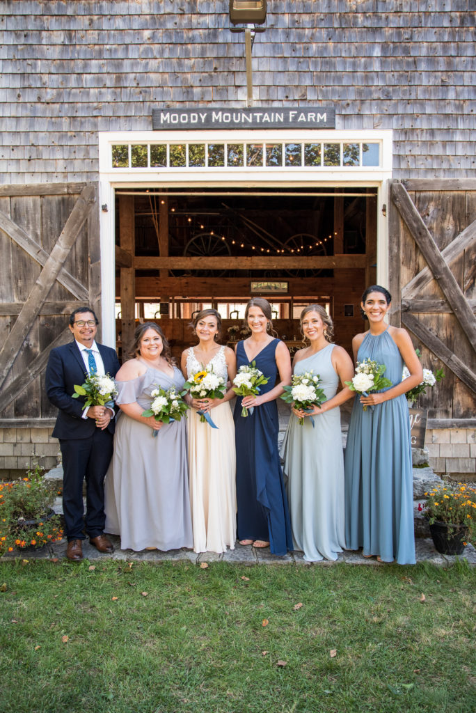 bride with her bridesmaids and bridesman standing in front of the barn at Moody Mountain Farm at a fall NH wedding