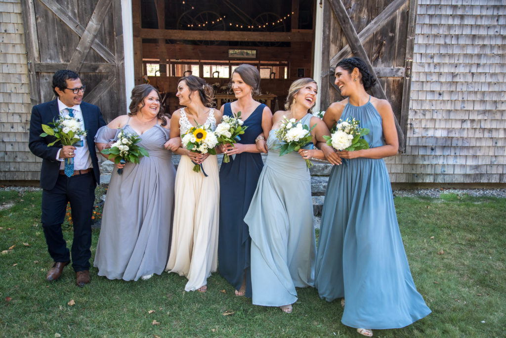 bride and her bridal party walking arm in arm smiling at each other