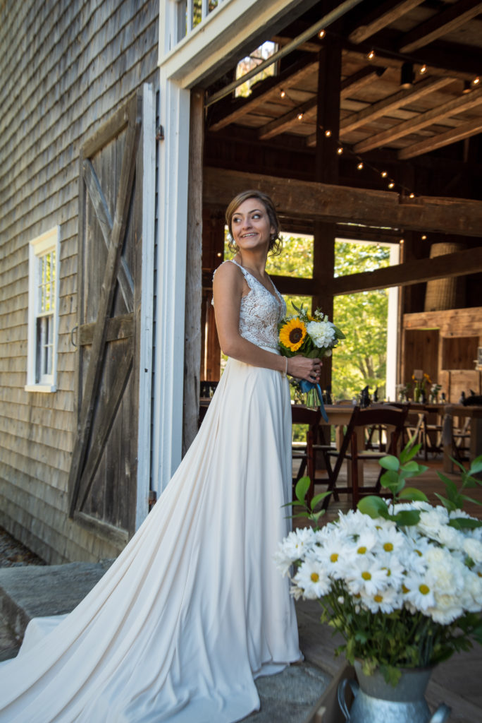 bride smiling at family as she stands on the steps of the barn