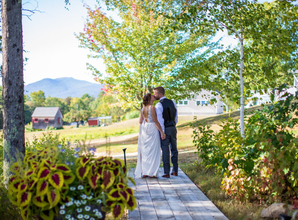 bride and groom kissing with mountains in the background at a fall NH wedding