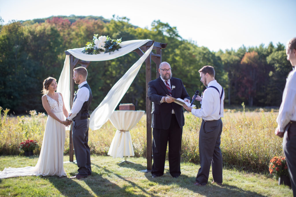 groomsmen reading what bride loves about groom as bride and groom smile at each other