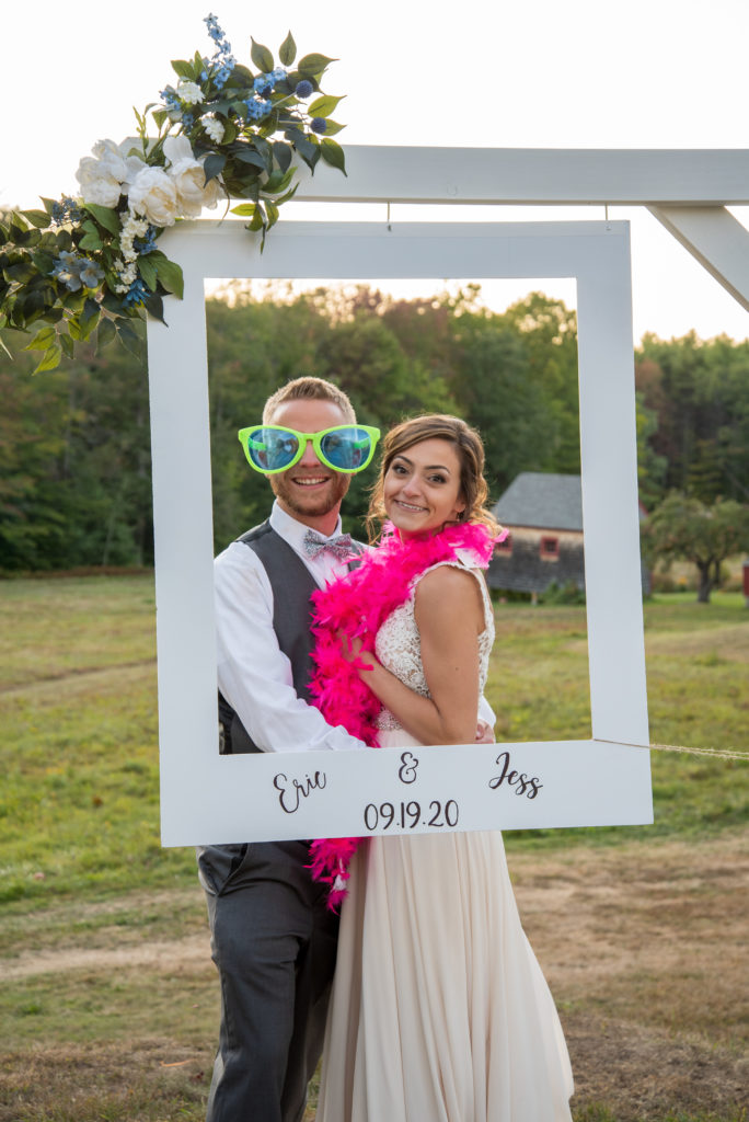 bride in a hot pink boa and groom in big funny sunglasses in a photo booth
