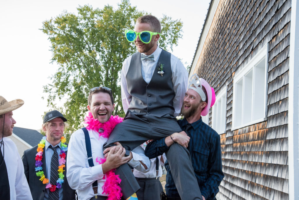 groom's friends picking him up and holding him on their shoulders