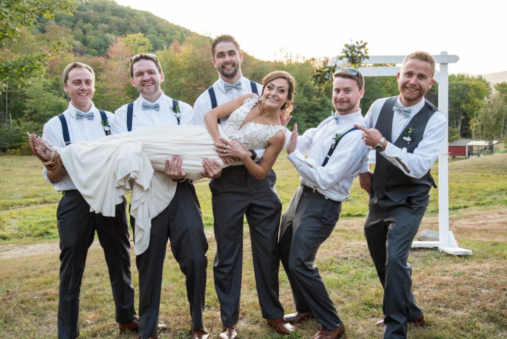 groomsmen holding the bride sideways 