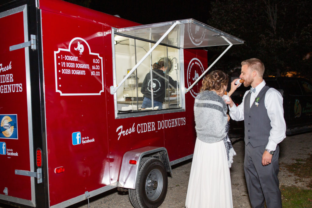 bride and groom feeding each other their apple cider donuts from the donut food truck at Barn at Moody Mountain Farm Wedding