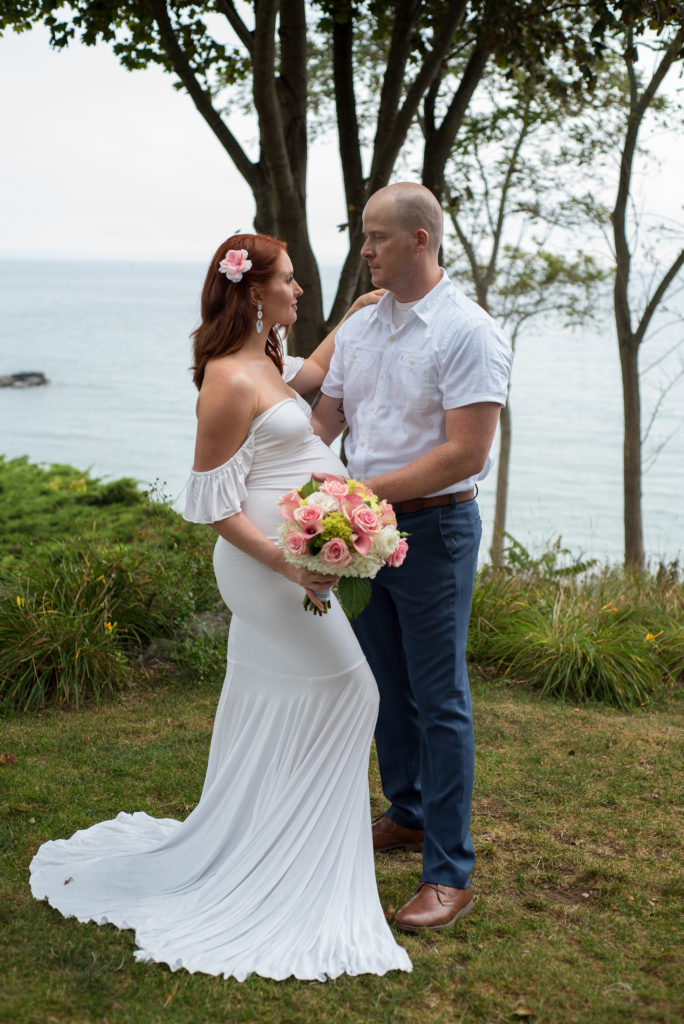 bride and groom looking at each other, standing in front of the ocean 