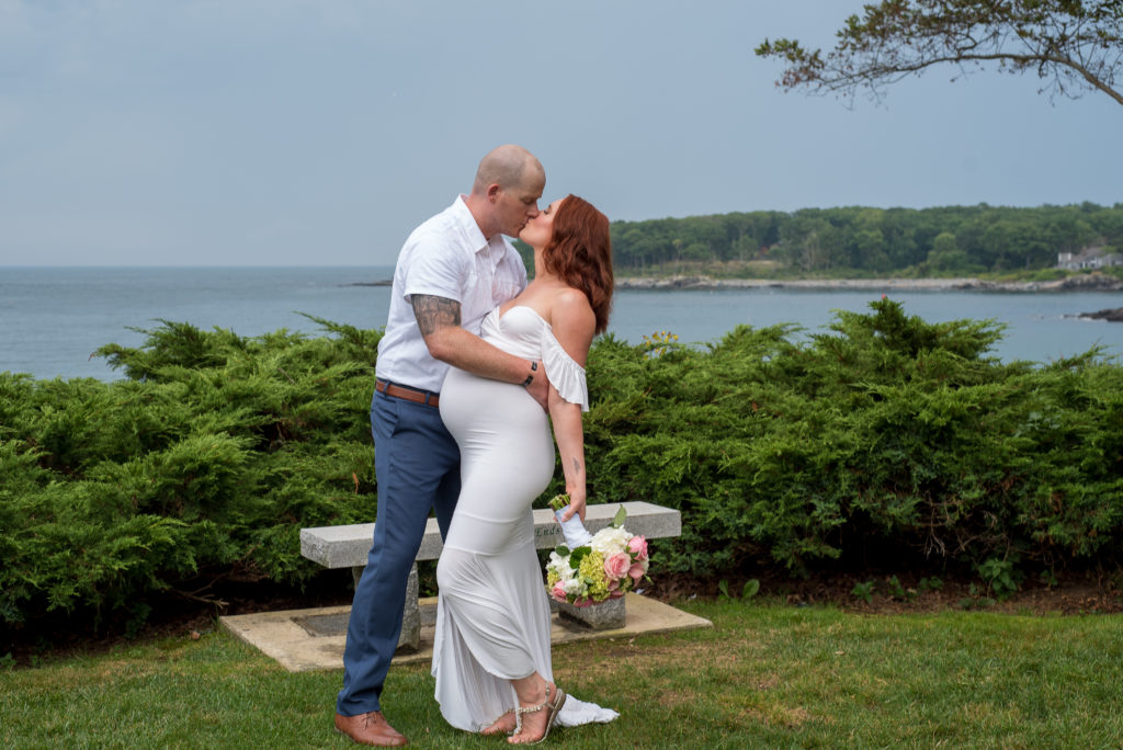 groom dipping bride to kiss in front of the ocean 