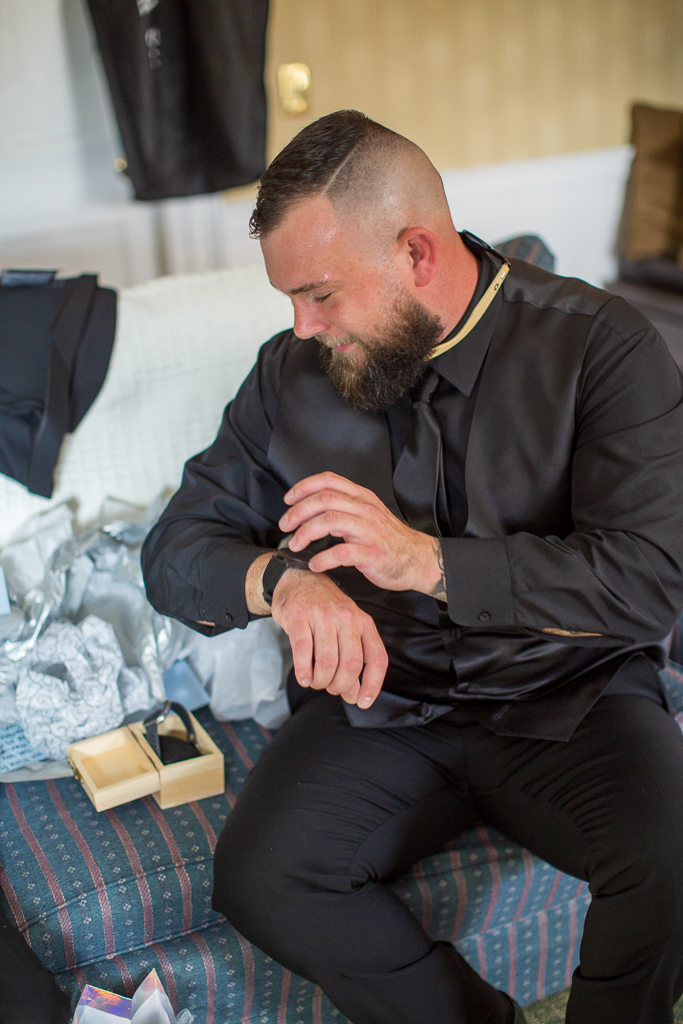groom opening gifts from the bride, putting on his watch