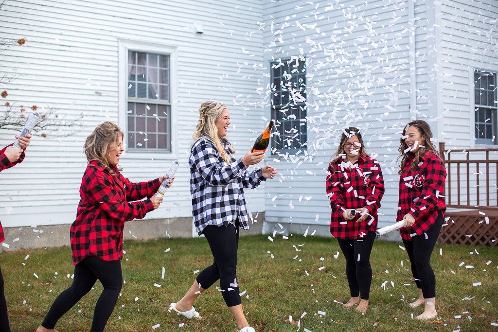 bride popping champagne while her girls pop confetti poppers at Whitney Farm Estate
