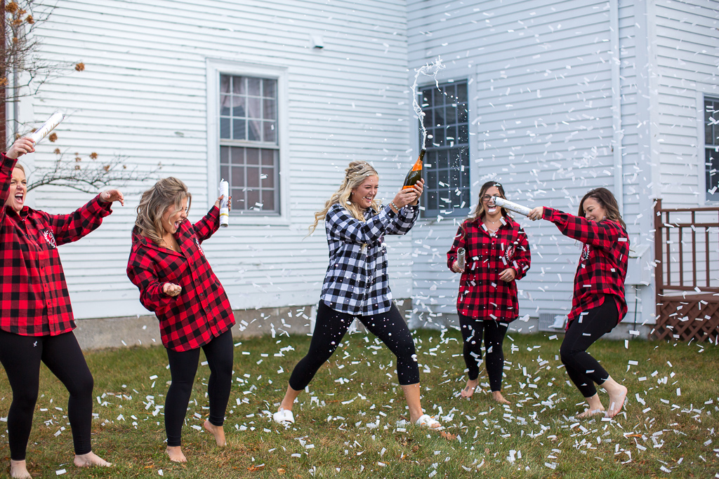 bride popping champagne while her girls use confetti poppers