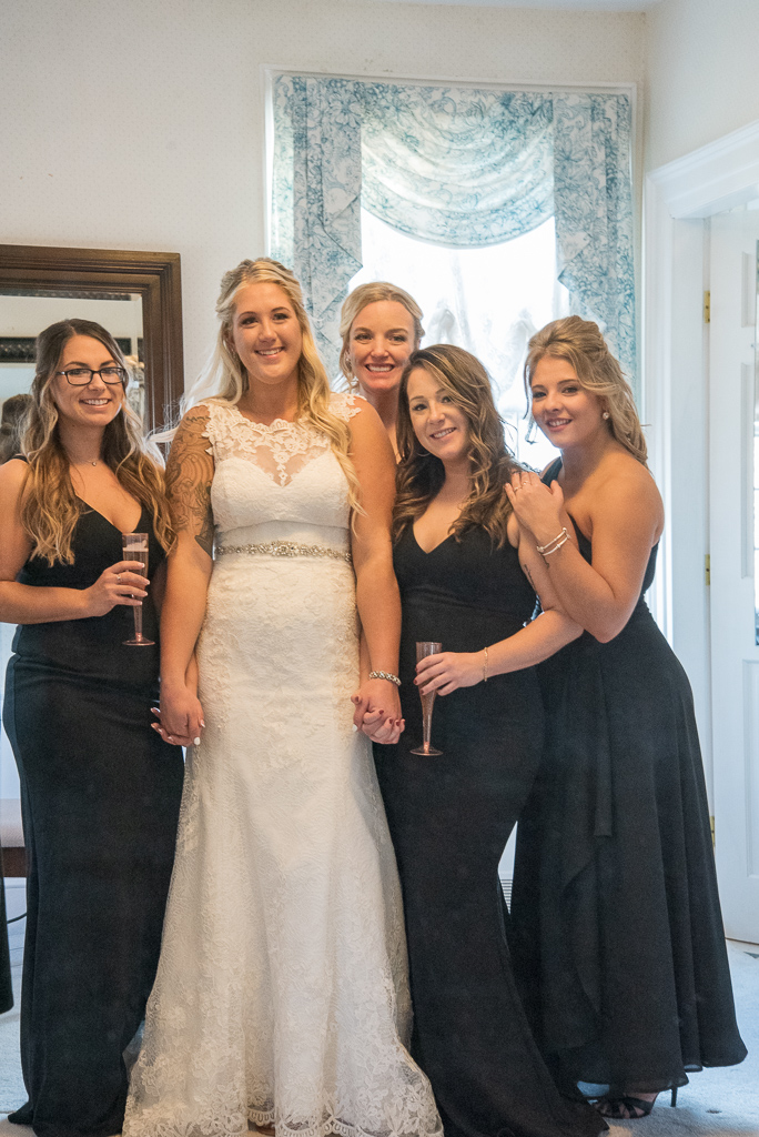 bride holding hands with her bridesmaids looking into the mirror