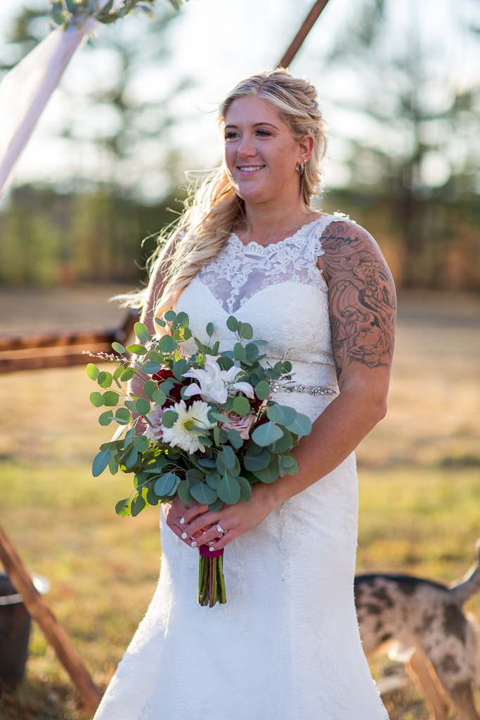 bride holding her bouquet standing in front of arbor