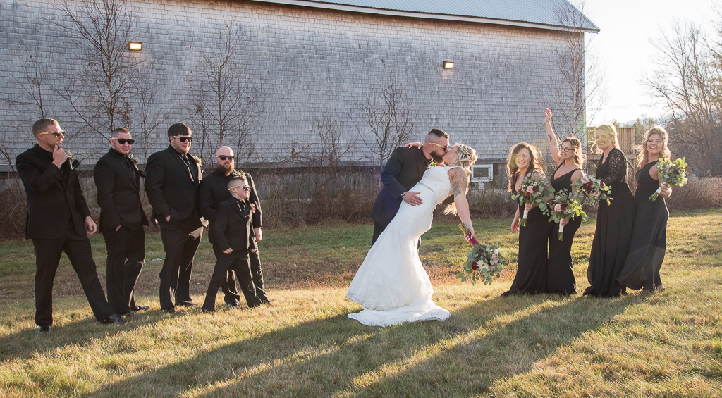 bride being dipped by groom with bridal party cheering behind them