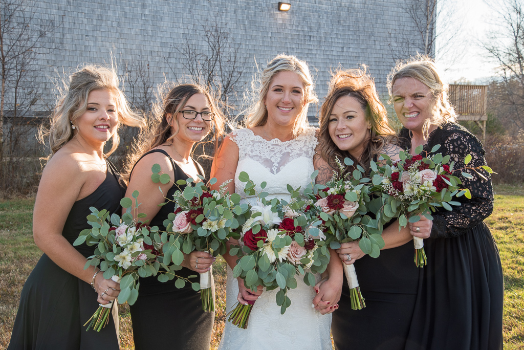 bride with her bridesmaids in front of the barn at Whitney Farm Estates