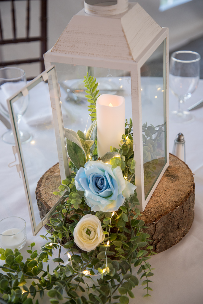 lantern centerpiece with blue flowers and a candle