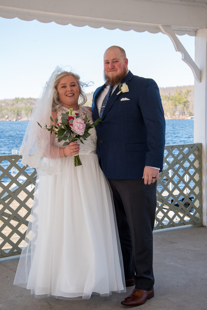 bride and groom standing on the gazebo with lake in the background