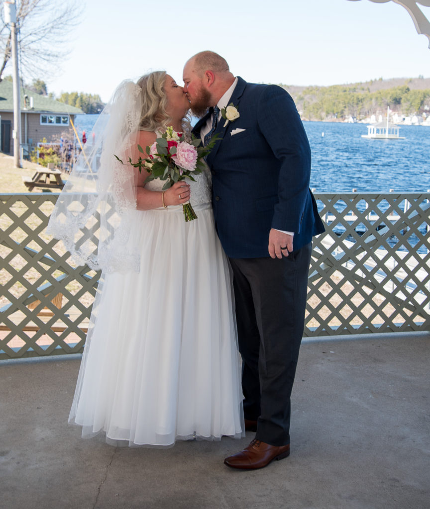 bride and groom kissing in front of the lake