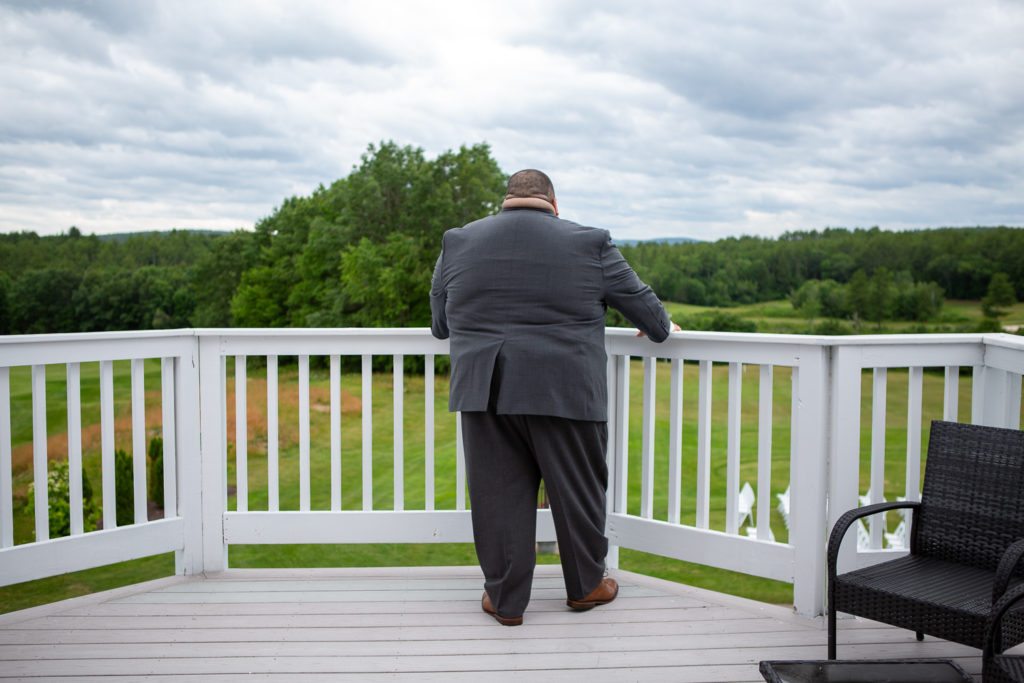 groom looking out at the mountains on the deck as he waits for his bride