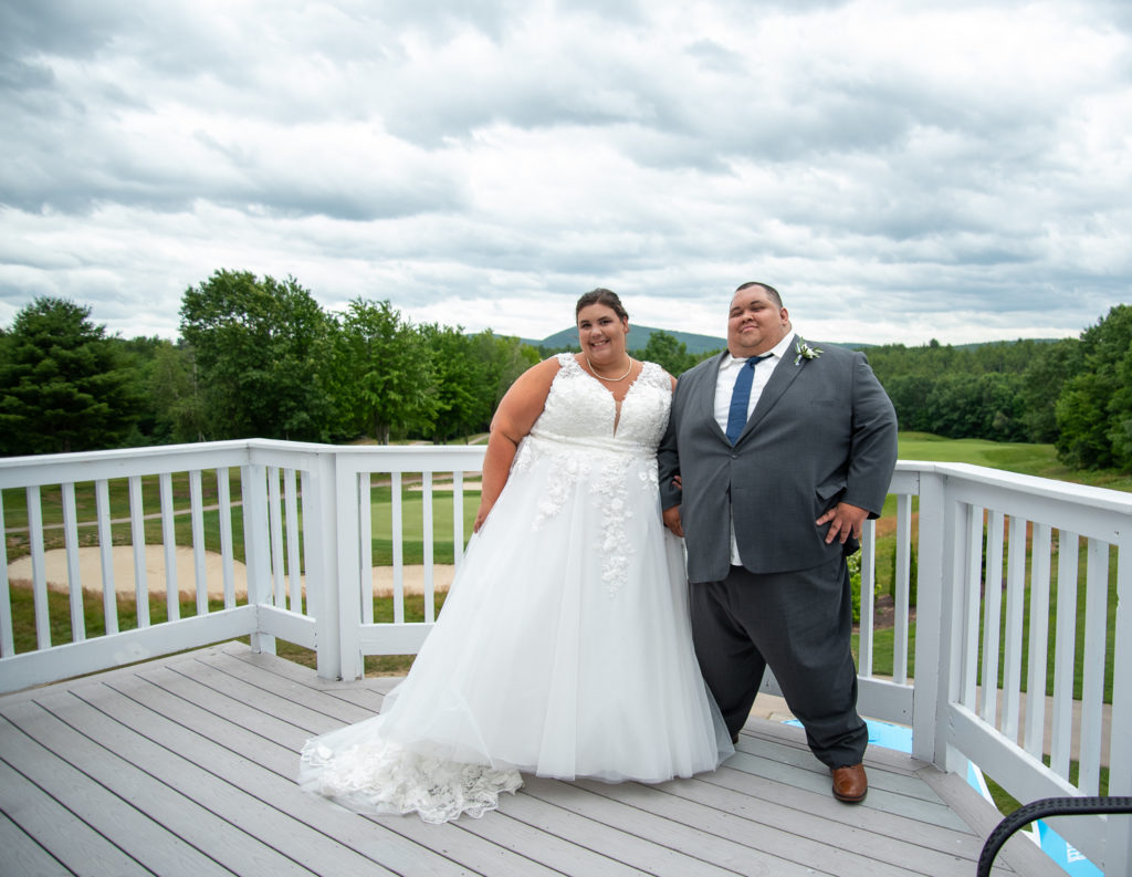 bride and groom posed on the deck with the mountains in the background at a summer loving wedding