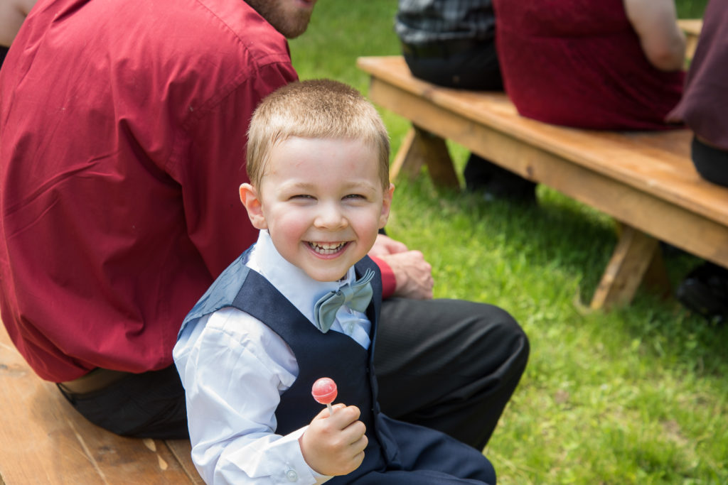 cute ring bearer watching the ceremony while eating a lollipop
