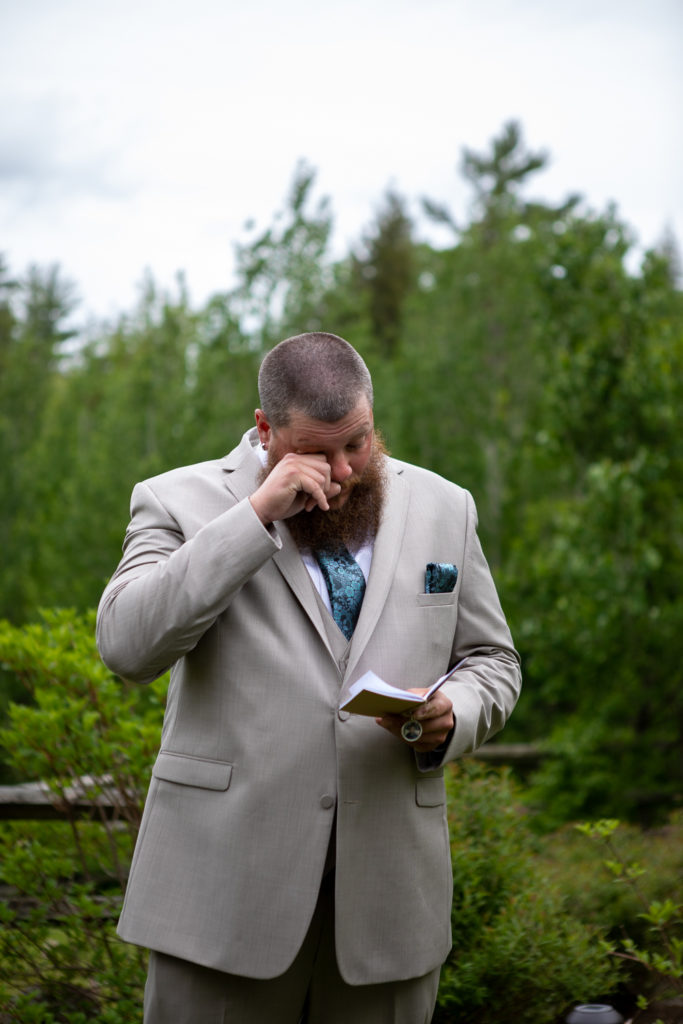groom wiping a tear from his eye as he reads the vows his wife to be wrote for him