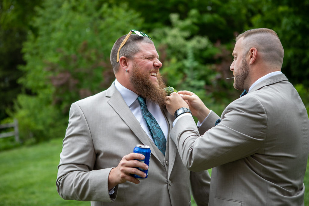 groomsman helping groom with his boutonnière