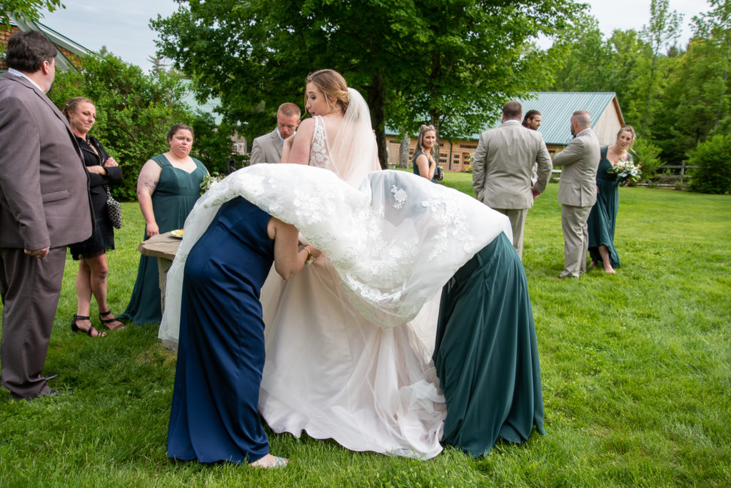 mom of bride and bridesmaid bustling the dress underneath the bride's ballgown