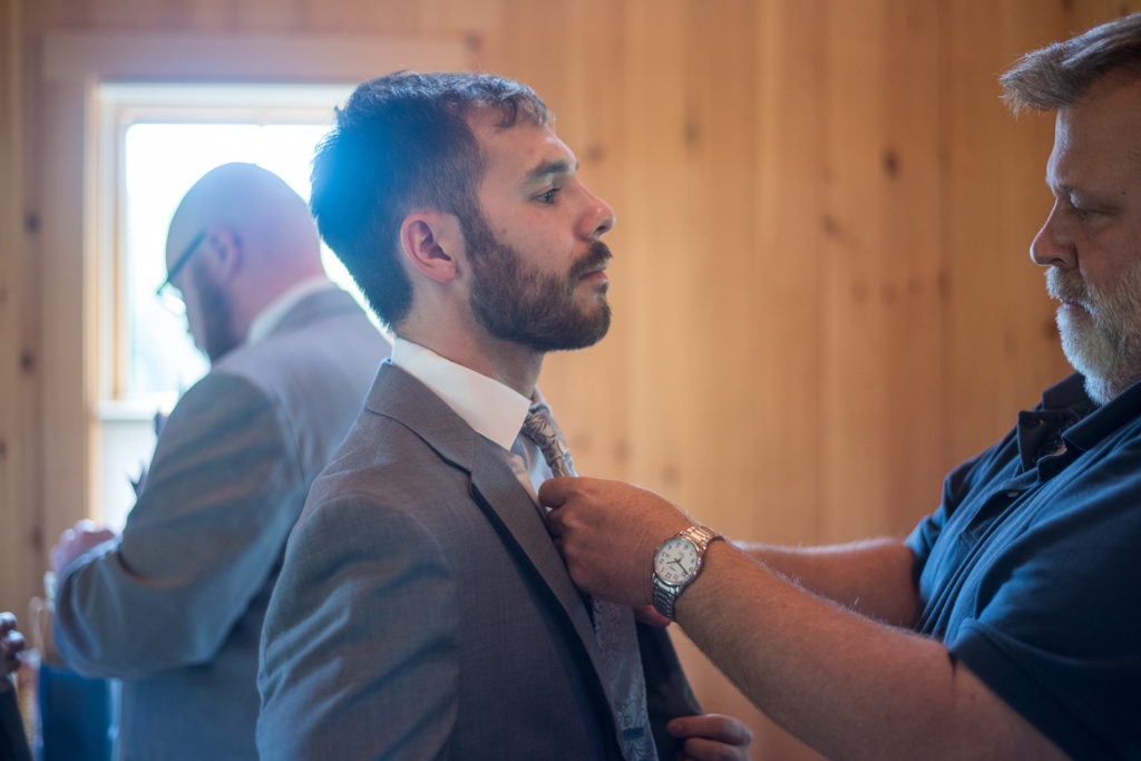 groom getting his tie adjusted by family before his NH summer barn wedding