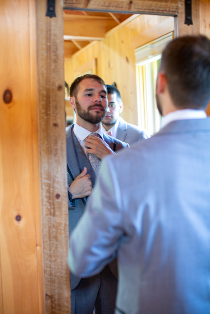 groom looking in the mirror adjusting his tie before the ceremony