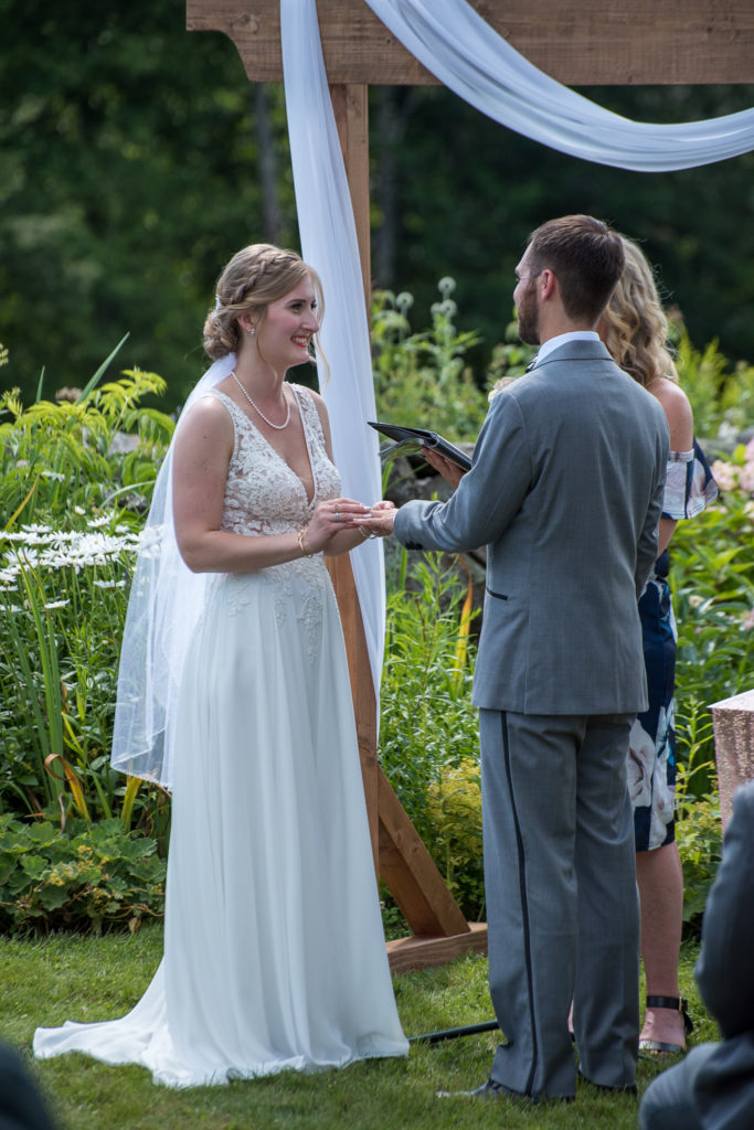 bride putting on groom's wedding ring during ceremony at NH barn summer wedding