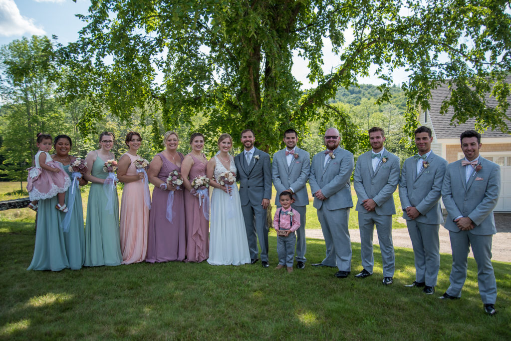 bridal party posing under a shade tree at NH summer barn wedding