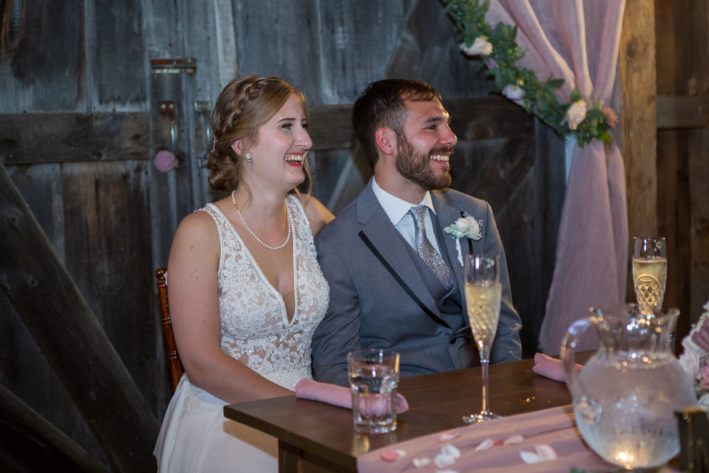 bride and groom laughing at best man speech at NH summer barn wedding