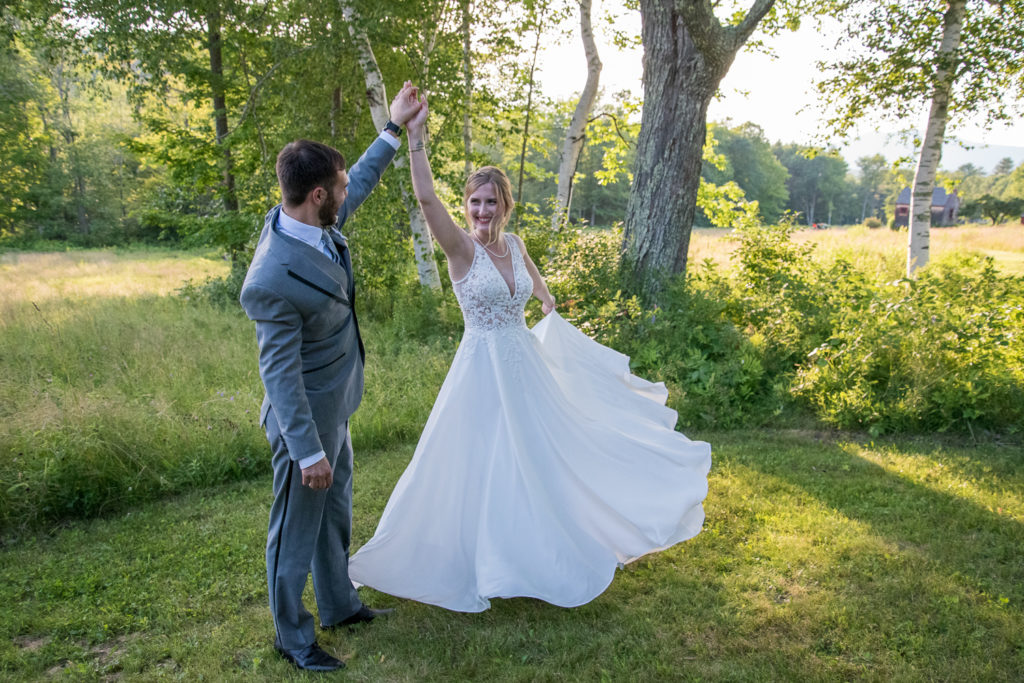 groom spinning his wife around in a field at NH summer barn wedding at Barn at Moody Mountain 