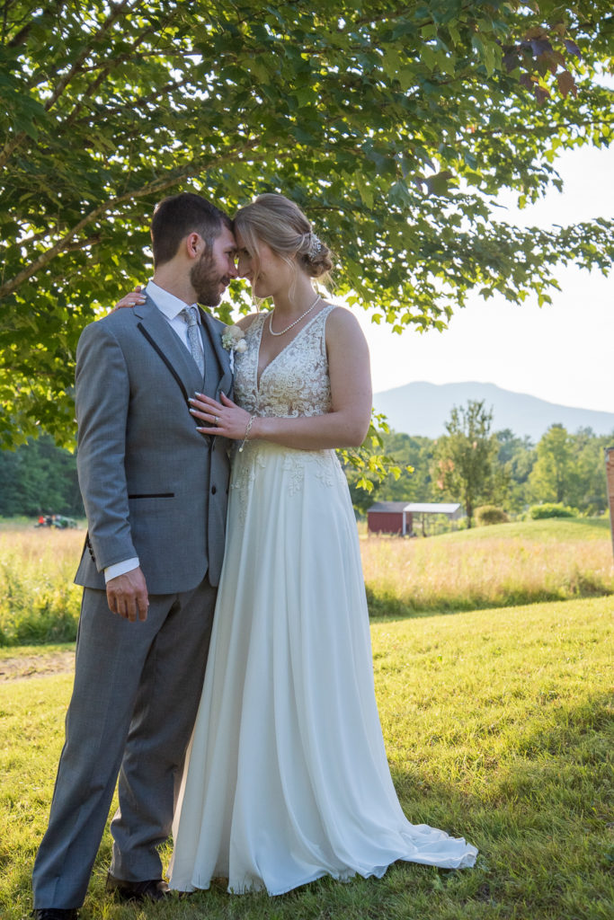  bride and groom posing with the mountains in the background at NH summer barn wedding