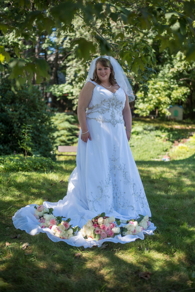 bride posing with wedding flowers on the train of the dress at The Oaks Somersworth NH wedding