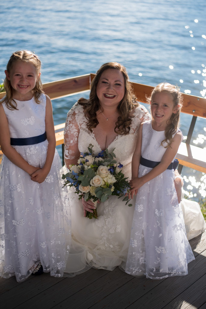 bride with her flower girls with lake in the background at wedding at the lake