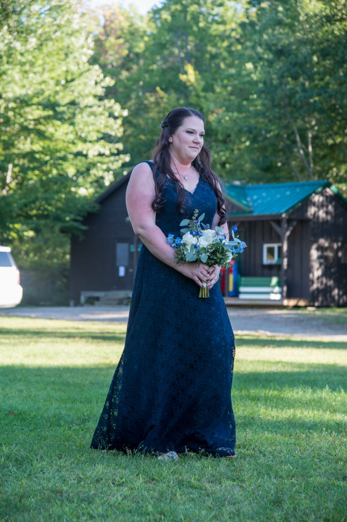 bridesmaid walking down the aisle at summer camp at wedding at the lake