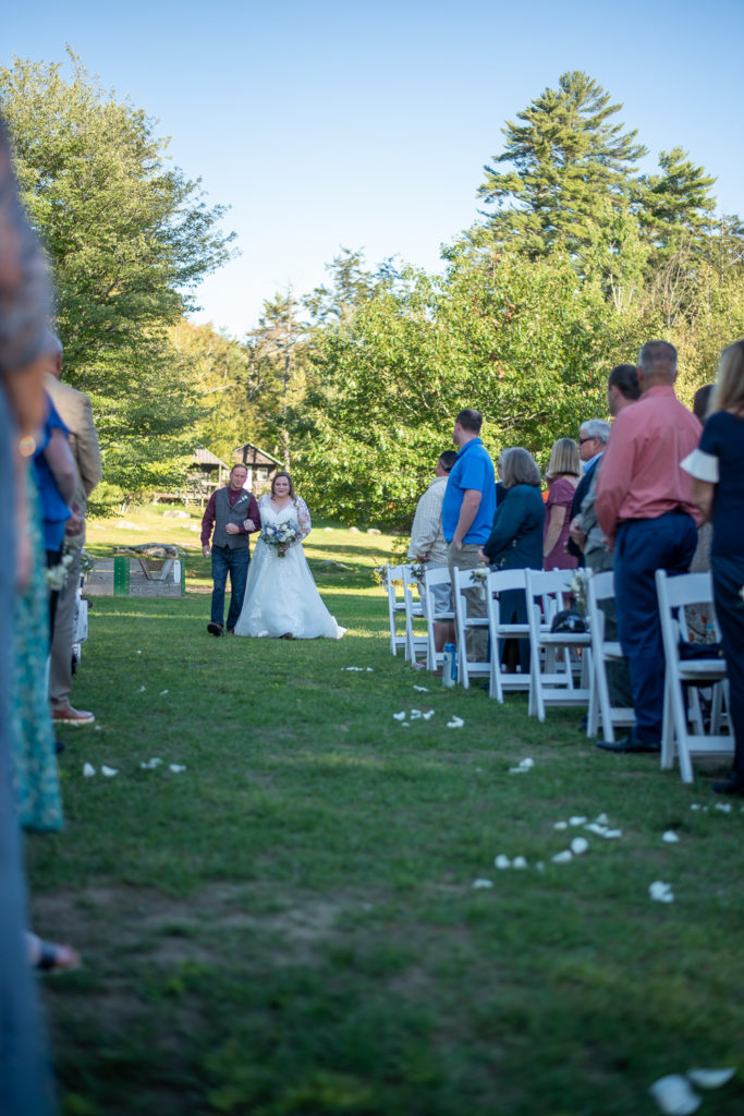 bride and her dad walking down the aisle at summer camp at wedding at the lake