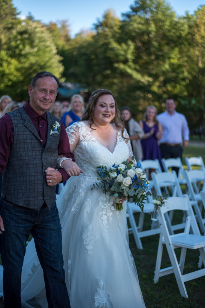 bride and her dad walking down the aisle at summer camp at wedding at the lake