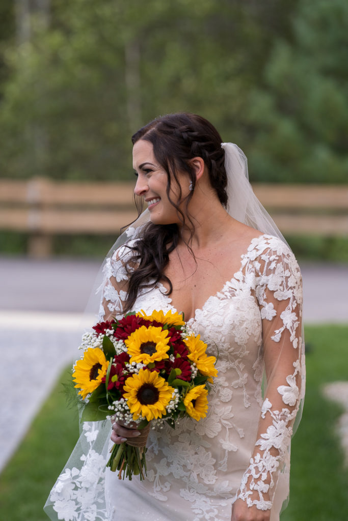smiling bride with her sunflower bouquet at fall wedding at the barn