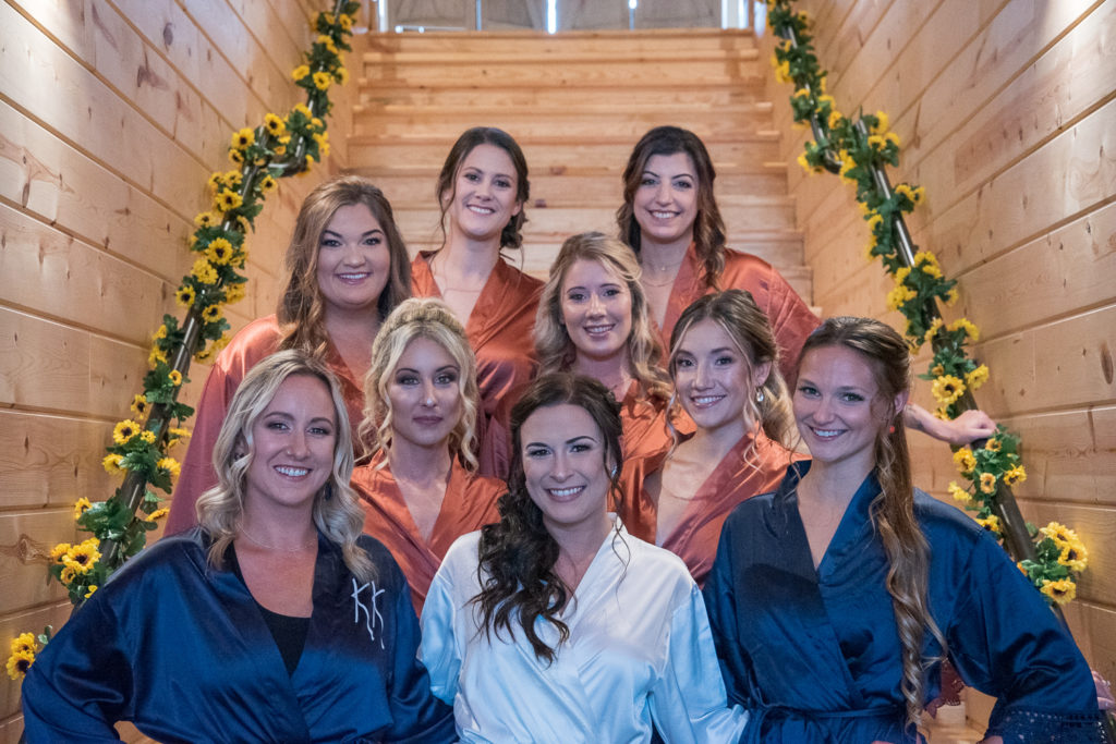 bride with her bridesmaids on the stairs at fall wedding at the barn at bull meadow
